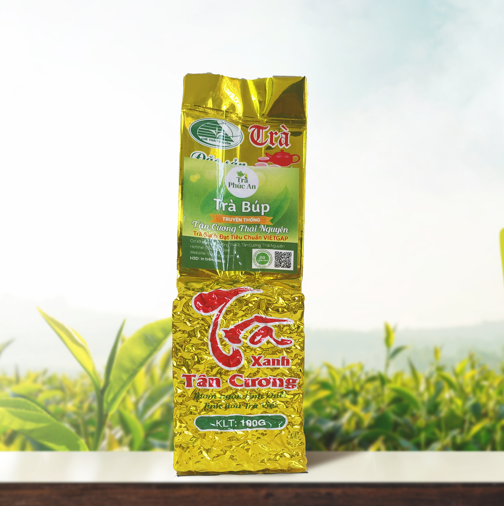 Bao bì Trà Búp Truyền Thống 100g màu vàng, chụp chính diện trên nền đồi chè.