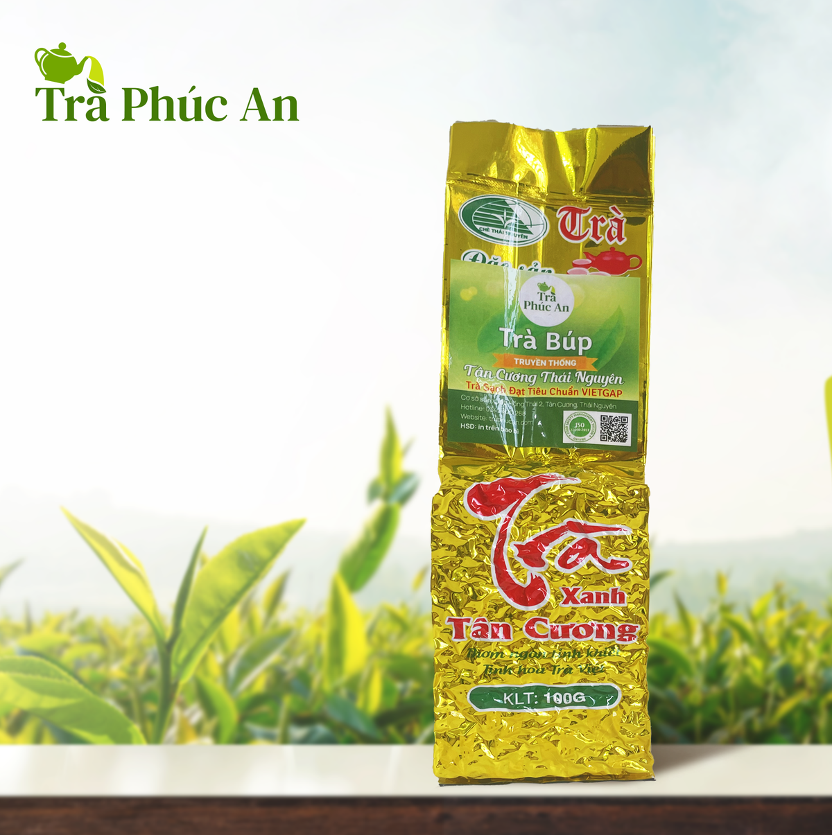 Gói Trà Búp Truyền Thống Phúc An 100g màu vàng, nhãn xanh, đặt trước nền đồi chè có logo Trà Phúc An.