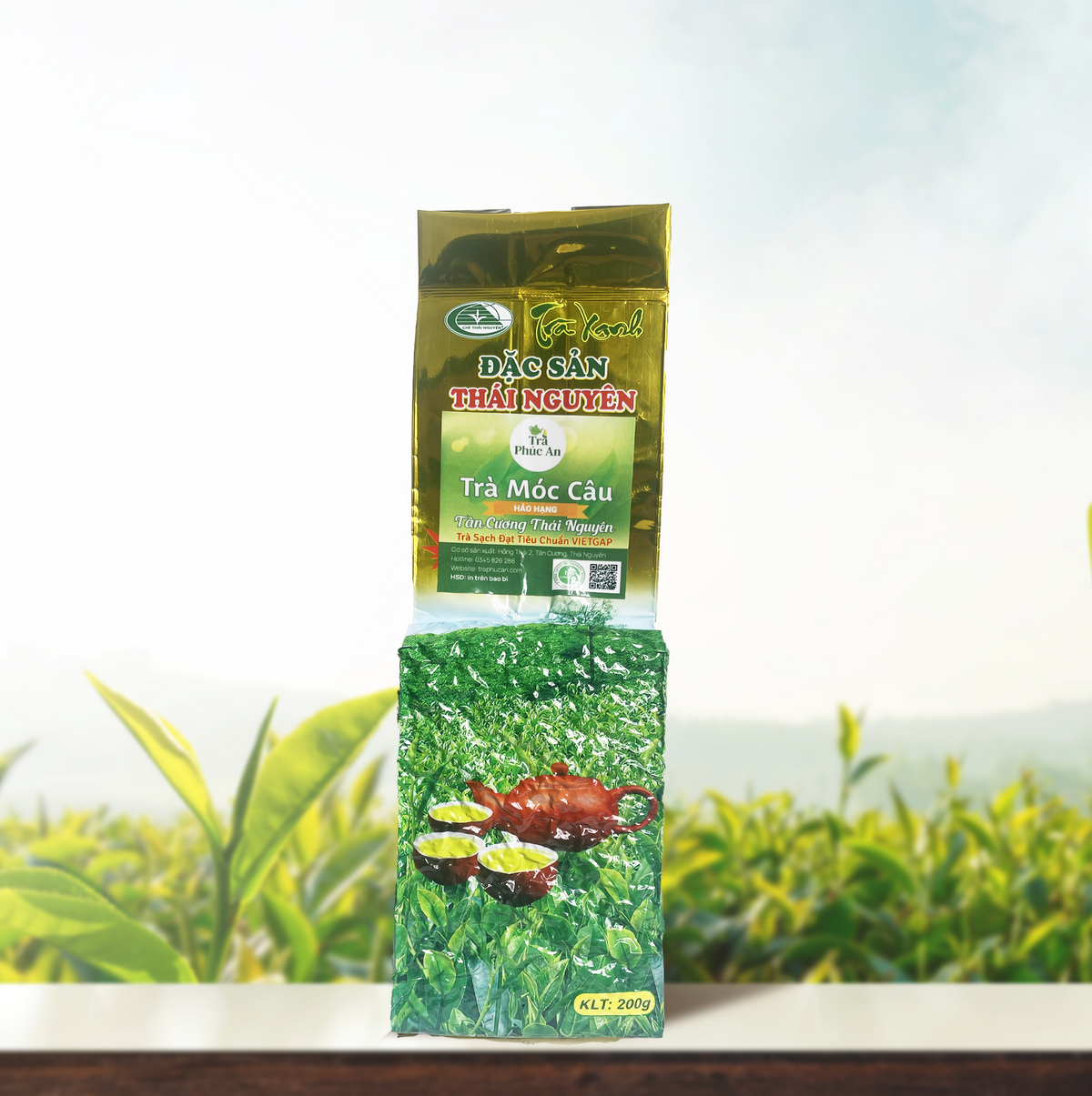 Gói Trà Móc Câu Hảo Hạng 200g màu xanh và vàng, đặt đứng trên nền đồi chè.