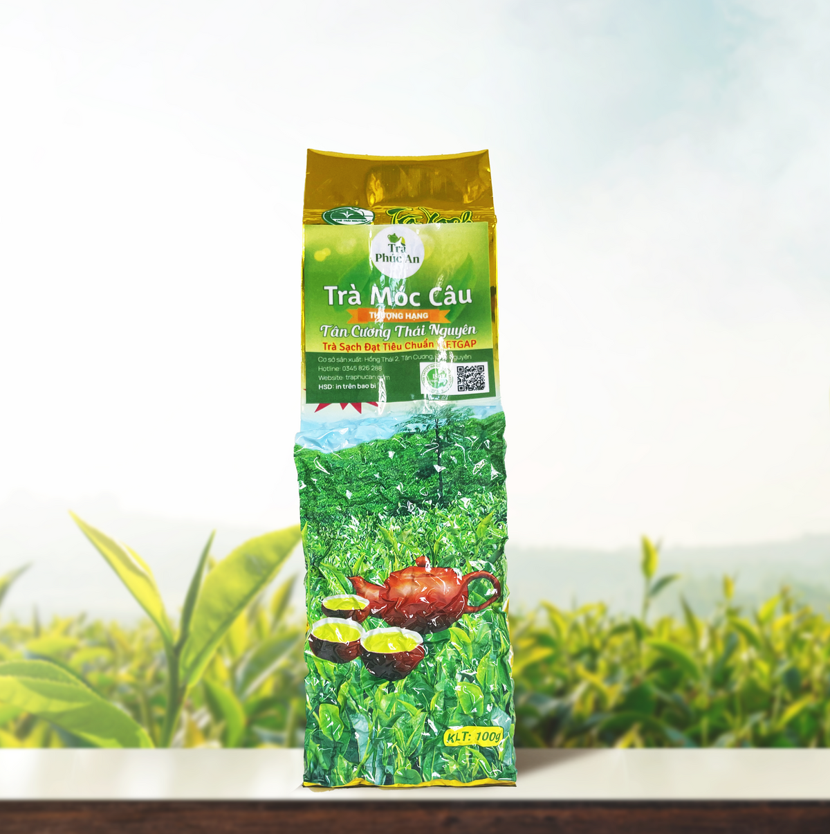 Bao bì Trà Móc Câu Thượng Hạng màu xanh và vàng, in hình ấm đỏ cùng các chén trà.