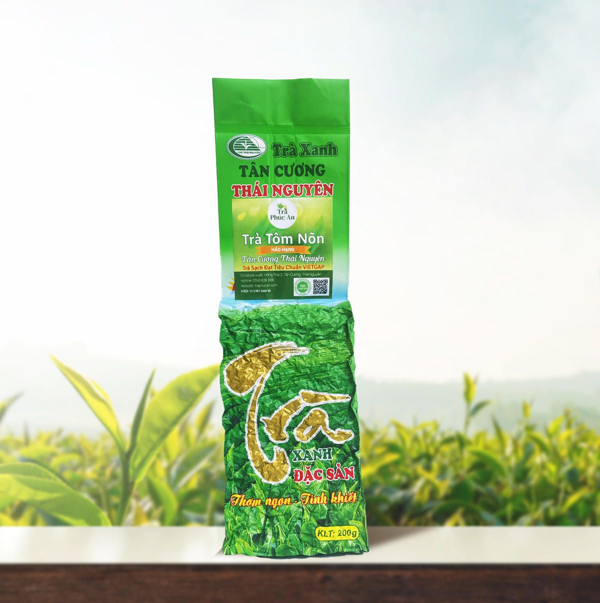 Gói Trà Tôm Nõn Hảo Hạng 200g màu xanh lá, chụp chính diện trước nền đồi chè.